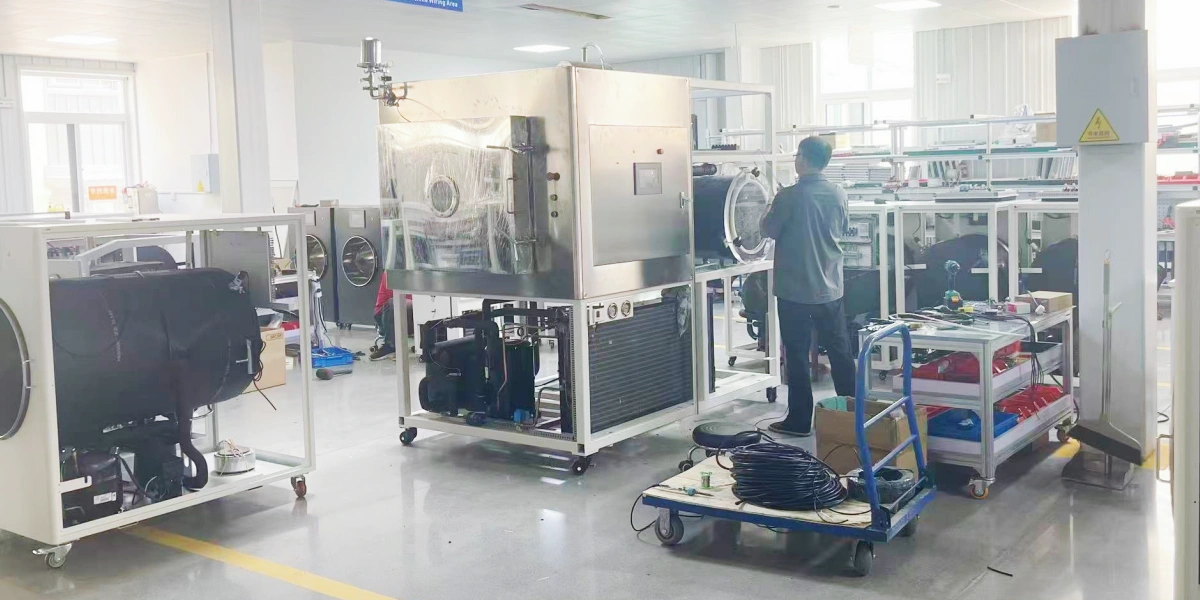 Technician assembling a pilot-scale freeze dryer with silicone oil heating system in manufacturing workshop